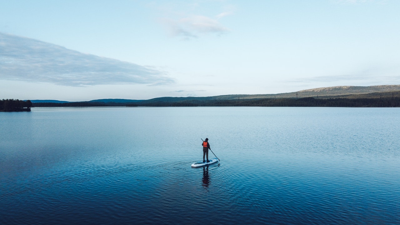 Ein Mann inmitten eines Sees auf einem Paddelboot